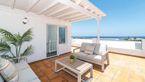 Un balcon avec un plafond blanc, un canapé, une table et une plante en pot.