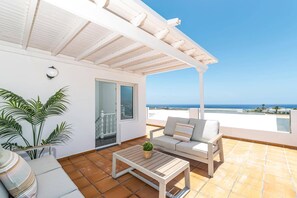 A balcony with a white ceiling, a sofa, a table, and a potted plant. - Villa Camino del Volcan by Villa Plus (Mácher)