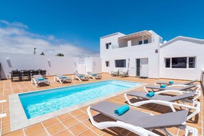A pool area with lounge chairs and a dining set. - Villa Camino del Volcan by Villa Plus (Mácher)
