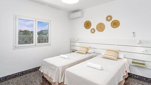 Une chambre avec deux lits, une fenêtre donnant sur un beau paysage et des œuvres d’art décoratives au mur.