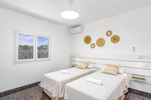 A bedroom with two beds, a window with a view, and decorative wall art. - Villa Camino del Volcan by Villa Plus (Mácher)