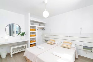 Une chambre moderne avec un grand lit, des rangements intégrés, une table de chevet et un miroir.