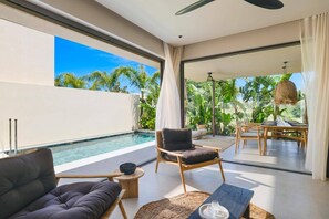 A modern room with a pool, a dining area, and a view of lush greenery. - Villa Terra Mare Zephyr by Villa Plus (Ialysos)