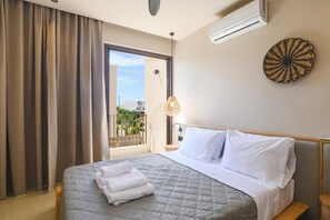 A hotel room with a bed, a window with curtains, an air conditioning unit, a wall-mounted lamp, and a decorative wall piece. - Villa Terra Mare Zephyr by Villa Plus (Ialysos)
