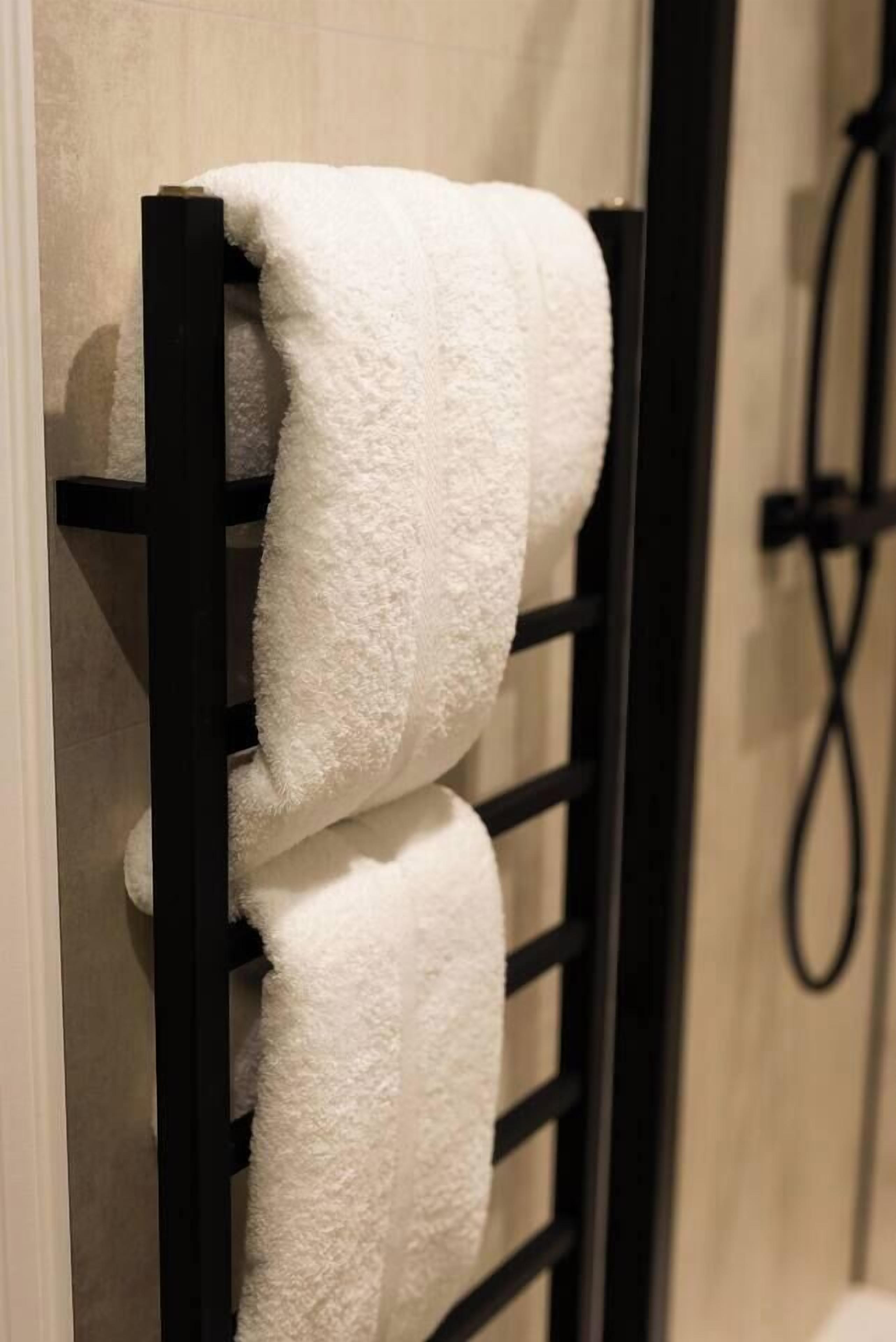 A black towel rack with two white towels.