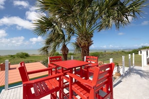 A red outdoor seating area with a view of the sea and palm trees. - Luxury waterfront retreat: Private Pool & SPI views (Port Isabel)