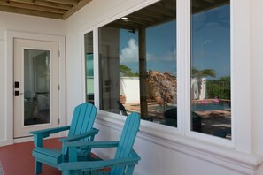 Ein Zimmer mit Glastür, die zu einem Außenbereich führt, einem Tisch mit Stühlen und Blick auf einen Swimmingpool.
