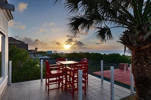 A terrace with a table and chairs, overlooking a coastal area with a sunset view. - Luxury waterfront retreat: Private Pool & SPI views (Port Isabel)
