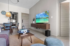 Ein modernes Wohnzimmer mit Flachbildfernseher, einer Essecke und einer Küche im Hintergrund.