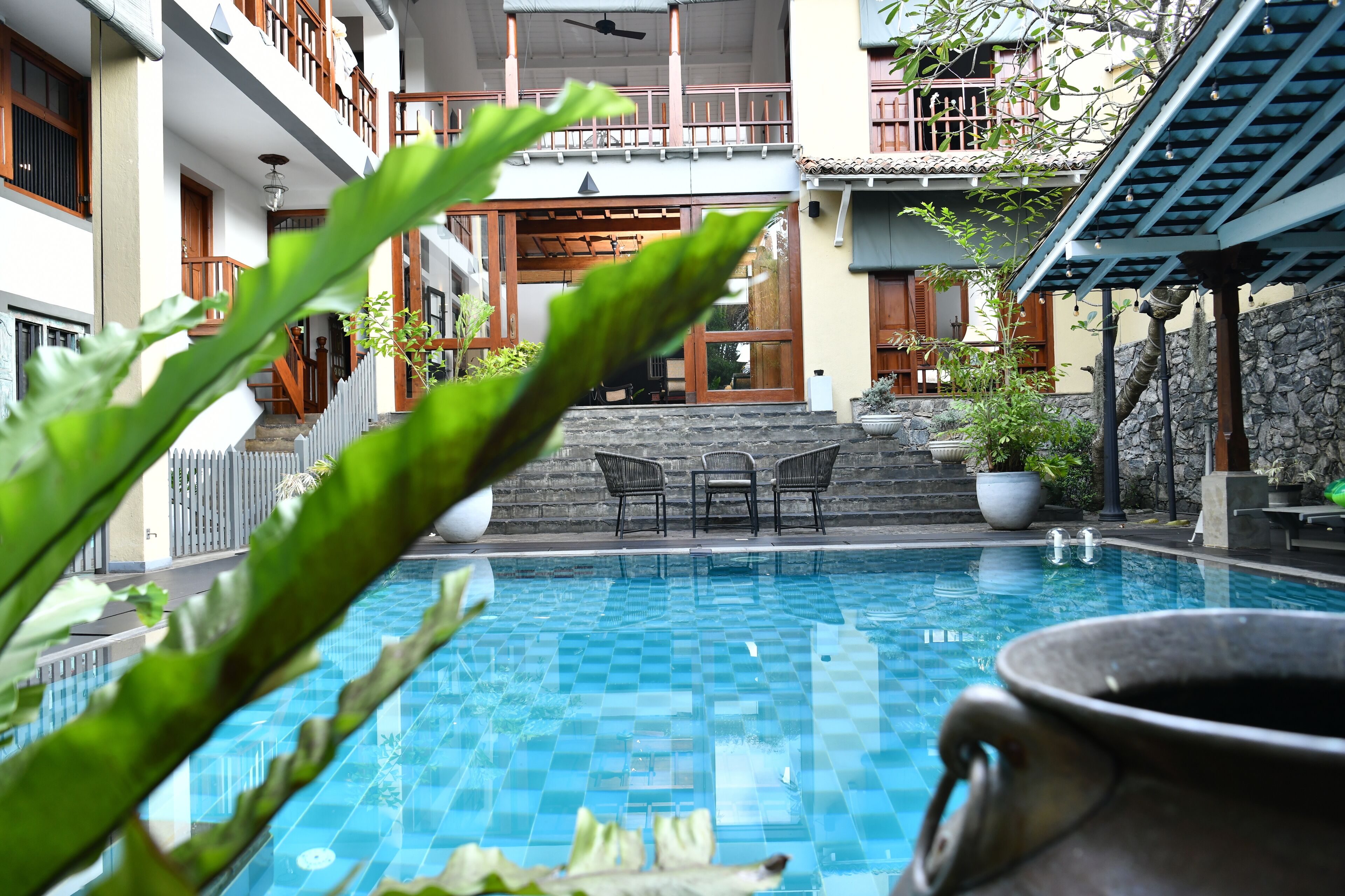 A pool with a checkered pattern, surrounded by potted plants and outdoor furniture.