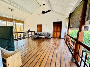 Un espace intérieur spacieux doté d’un plancher en bois, d’un canapé, d’une télévision et d’un ventilateur de plafond.