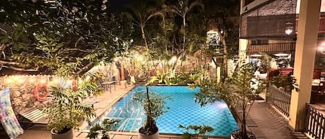 Uma piscina ao ar livre rodeada por plantas em vasos e um caminho de pedra.