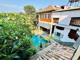 Un edificio residencial con piscina, rodeado de abundante vegetación.