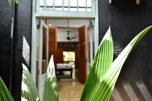 Un couloir avec un lit, un ventilateur de plafond et une fenêtre.