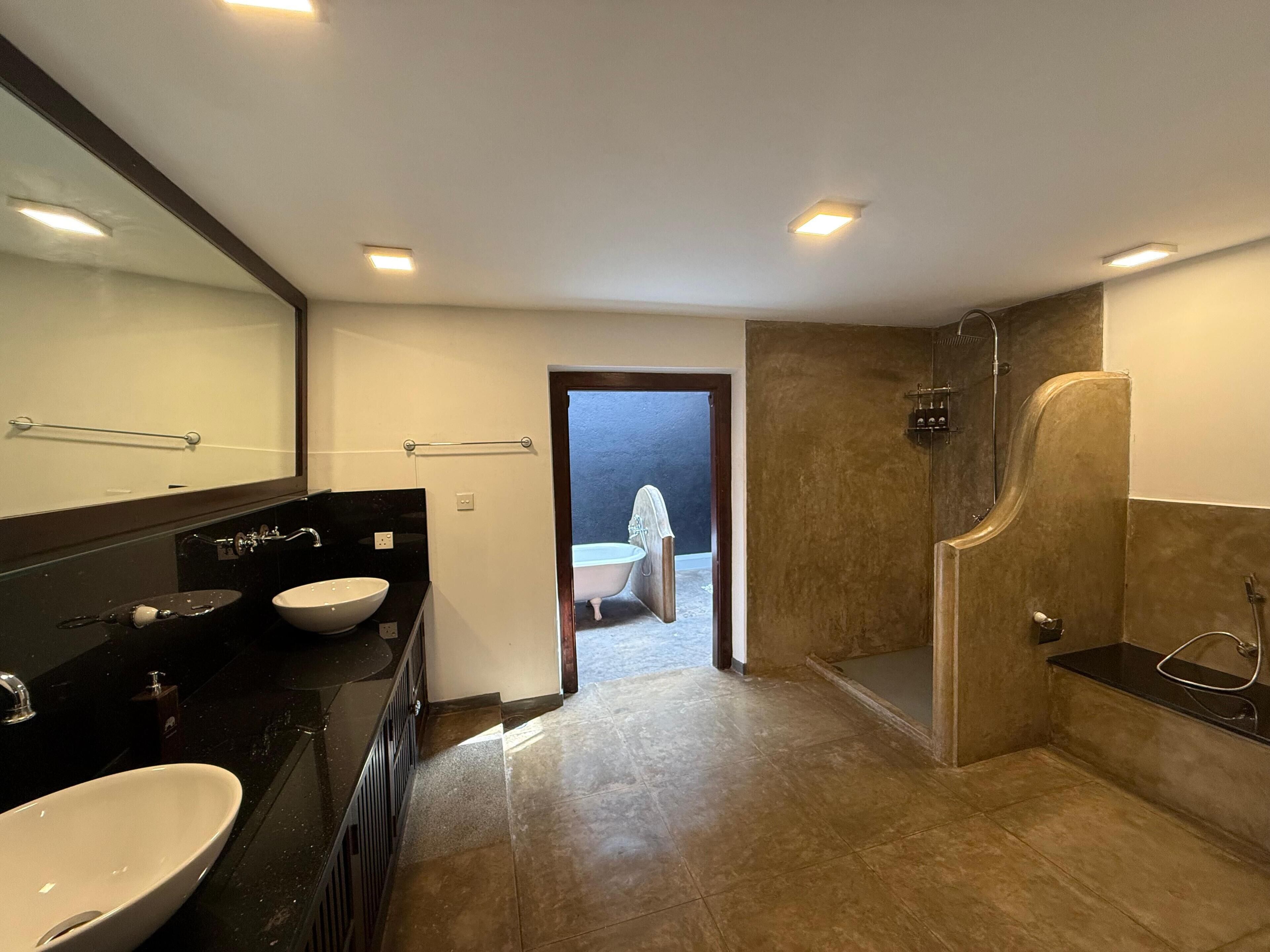A modern bathroom with a large mirror, a sink, and a shower area.