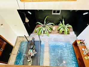 Um quarto com piso de azulejos azuis, uma scooter, um armário de madeira e um arranjo de plantas.