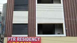 Um edifício de vários andares com uma placa que indica 'PTR RESIDENCY ROOMS A/C', informando sobre quartos com ar condicionado.