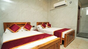 Quarto de hotel com duas camas de madeira, paredes de mármore e ar condicionado.