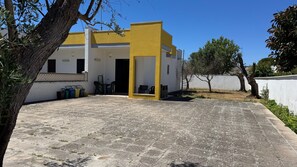 A building with a yellow facade, a paved courtyard, and a white wall.