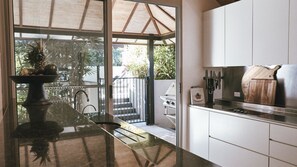 Eine moderne Küche mit großem Fenster, Grillplatz außen und Essbereich mit Tisch und Stühlen.