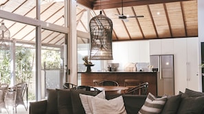 A modern kitchen with white cabinets, a wooden ceiling, and a hanging light fixture. - Grand Luxe Villa B - 19B Gordon St (Byron Bay)