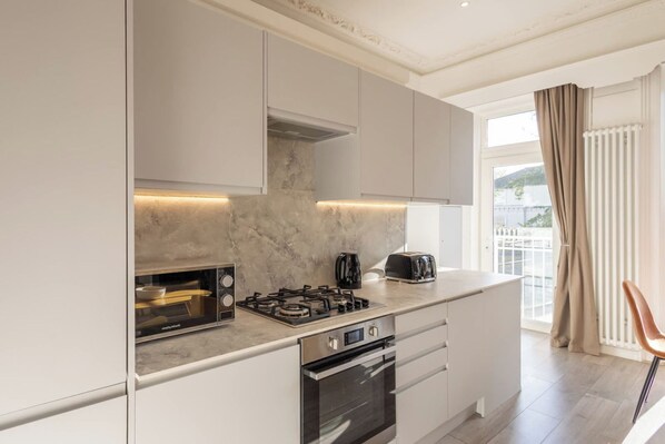 A modern kitchen with a built-in oven, a gas stove, a toaster, and a microwave. - Boutique Eastbourne Gem (Eastbourne)
