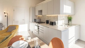 A modern kitchen with white cabinets, a built-in oven, a microwave, and a toaster. - Boutique Eastbourne Gem (Eastbourne)