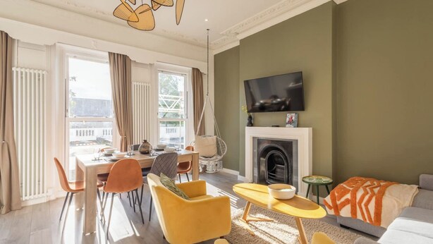 A modern living room with a dining area, a fireplace, and a television mounted on the wall. - Boutique Eastbourne Gem (Eastbourne)
