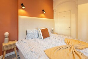 A bedroom with a bed, bedside lamps, a nightstand, and a door. - Boutique Eastbourne Gem (Eastbourne)