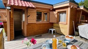 A wooden cabin with a patio, a table with breakfast items, and a clear blue sky. - Le Nid des Cimes - Cottage for 6 people - Aussois (Aussois)