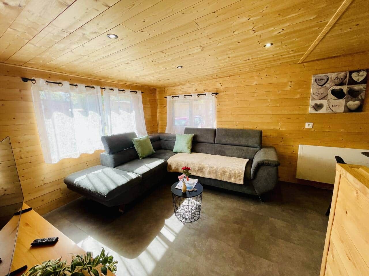 L’intérieur d’un chalet chaleureux, avec un canapé, une petite table ronde et un radiateur.