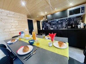 Ein Essbereich mit einem für das Frühstück gedeckten Tisch, darunter Croissants, eine Karaffe und eine Kaffeemaschine.