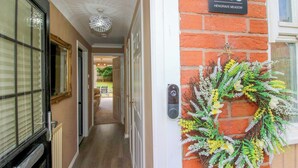 A hallway with a door labeled '18 HENGRAVE MEADOW,' a decorative wreath, and a chandelier.