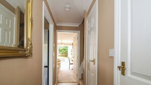 A hallway with a mirror, a door with a brass handle, and a carpeted floor.