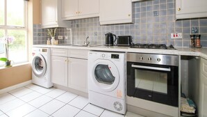 A kitchen with white cabinets, a washing machine, a stove, and a microwave.