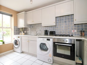 A kitchen with white cabinets, a washing machine, a stove, and a microwave.