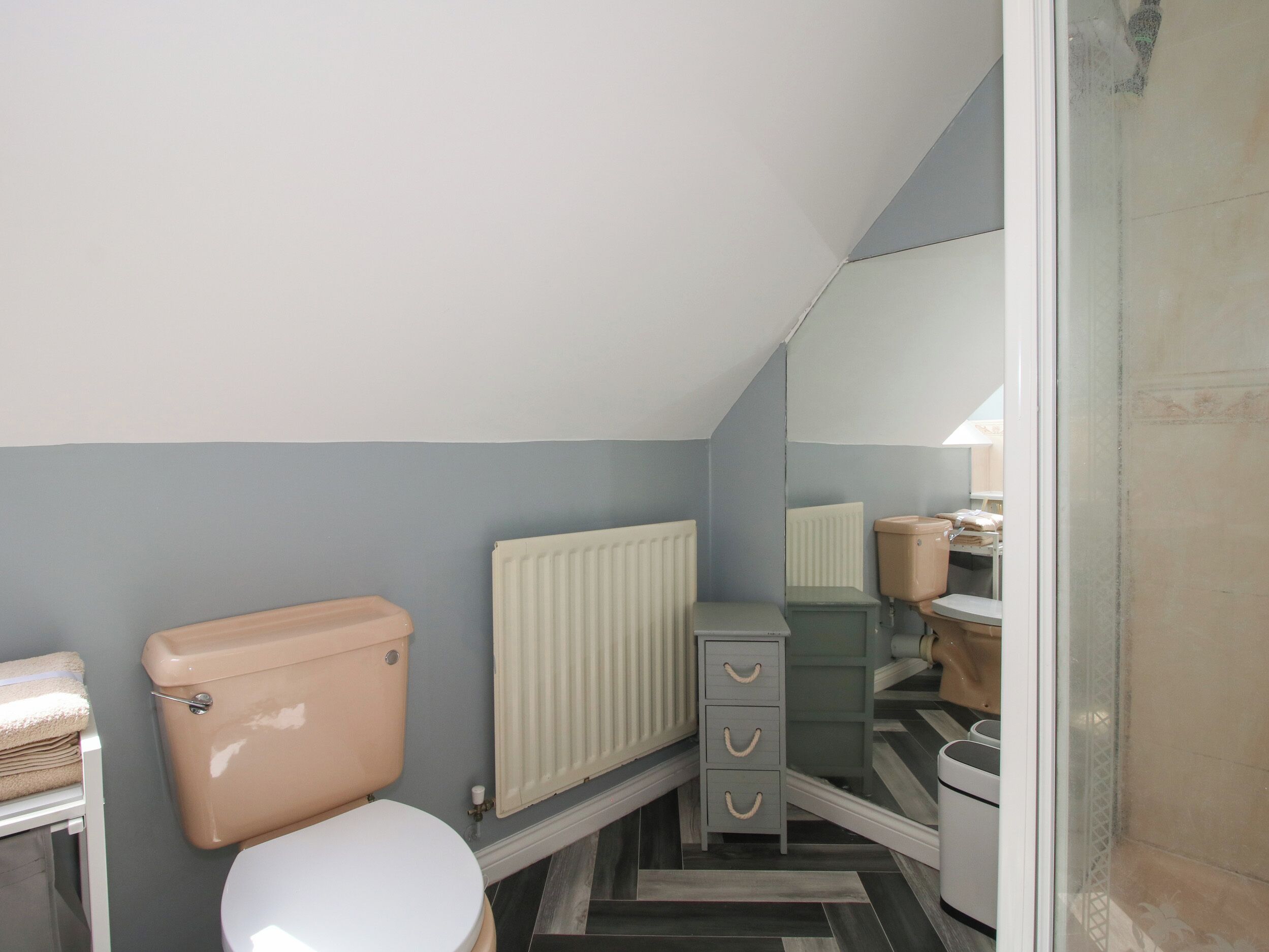 Une petite salle de bain avec des toilettes, un radiateur et un miroir.