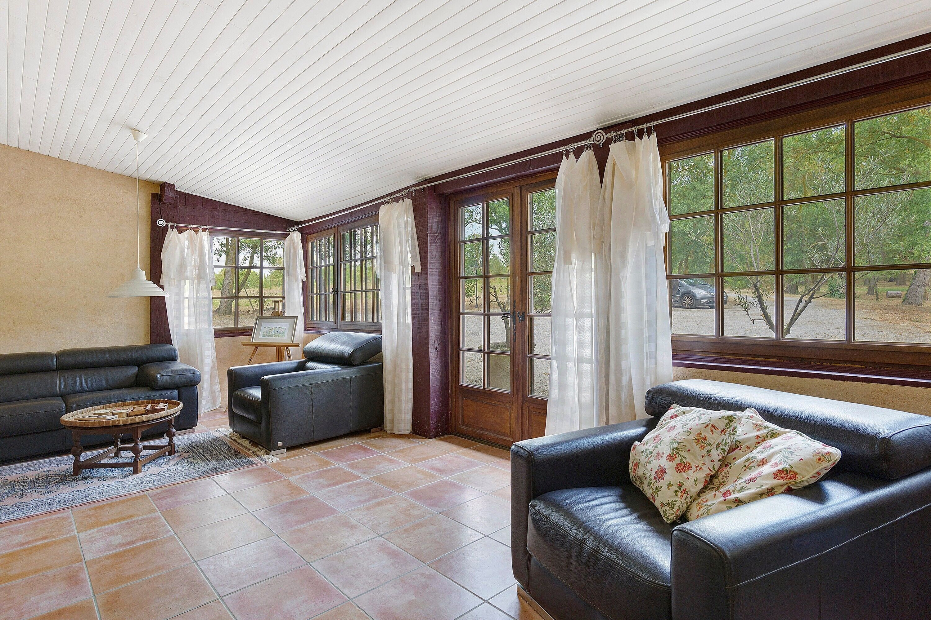 A sunlit room with a sofa, a small table, and a window with curtains.