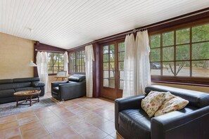 A sunlit room with a sofa, a small table, and a window with curtains.