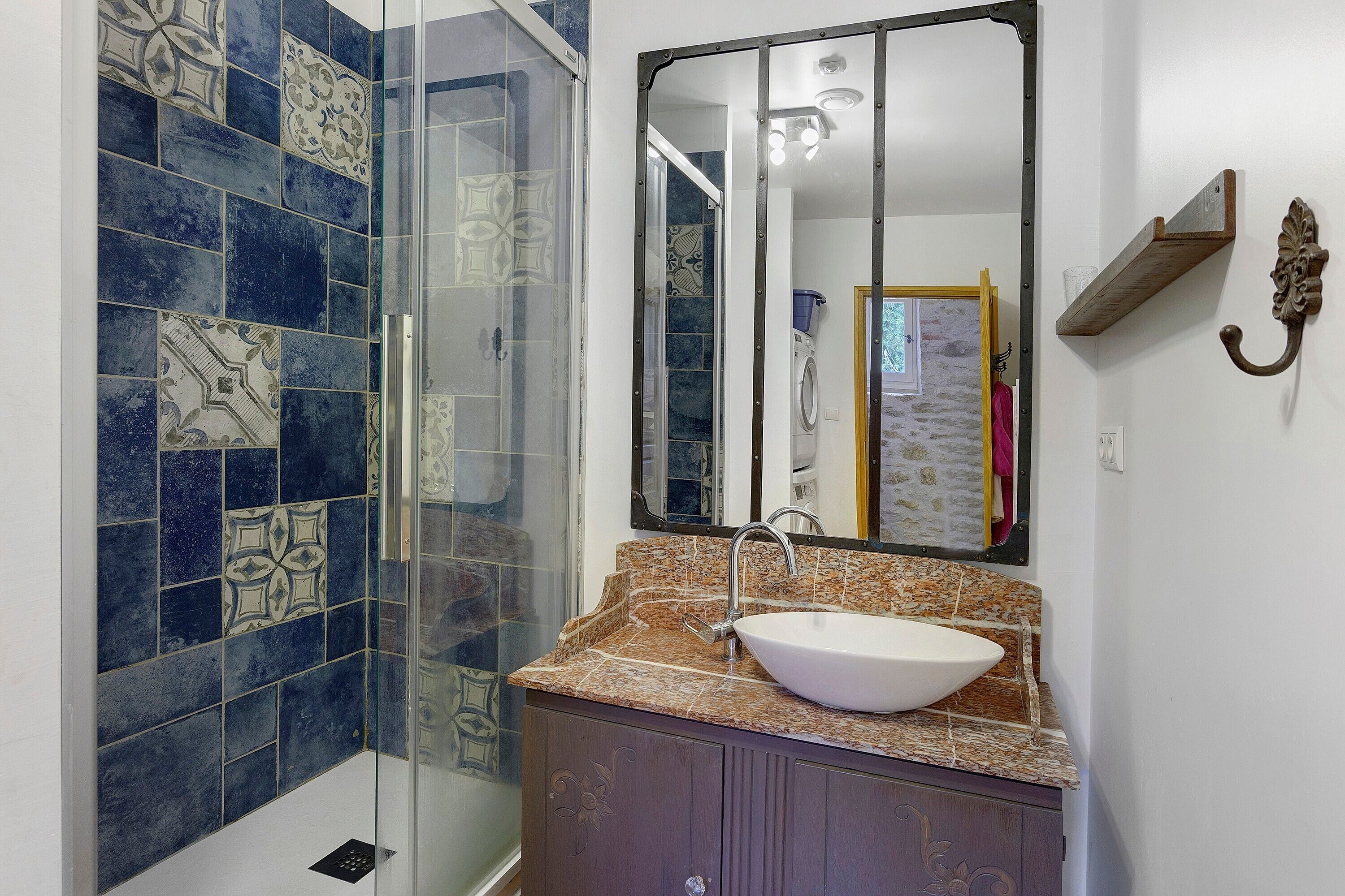 Un baño con cabina de ducha de vidrio, un lavabo con encimera de mármol y un espejo sobre el lavabo.