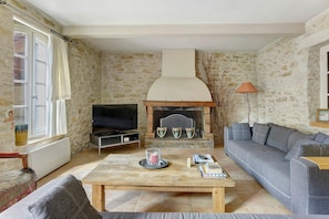 Ein Wohnzimmer mit Steinwand, Kamin, Fernseher, Sofa und Couchtisch.