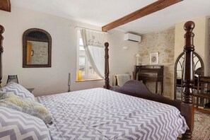 Ein Schlafzimmer mit Bett, Schreibtisch, Stuhl und einem Fenster mit Vorhängen.