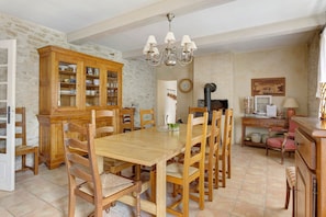 Un coin repas avec une table et des chaises en bois, un buffet avec des portes en verre, un lustre et une horloge au mur.