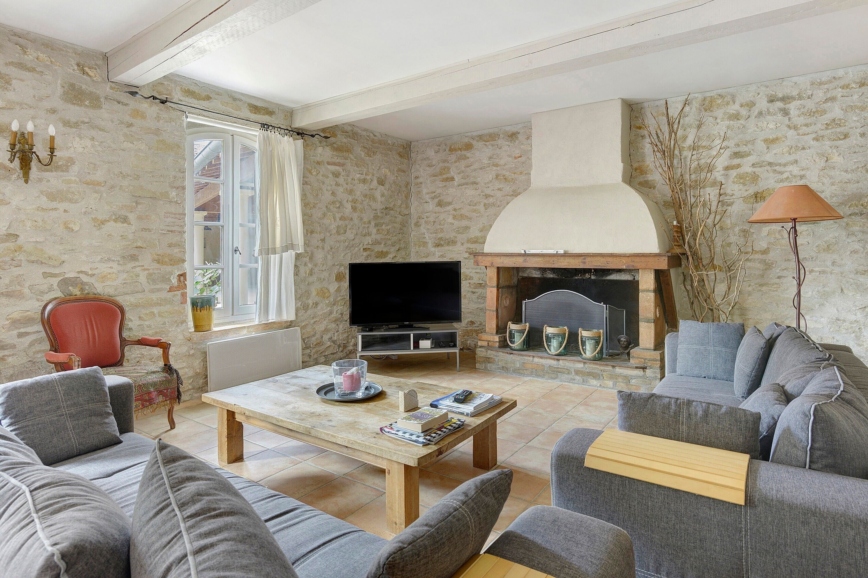Un salon avec un mur en pierre, une cheminée, un téléviseur et un canapé.