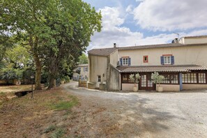 A traditional building with a gravel driveway, a small garden, and a tree.
