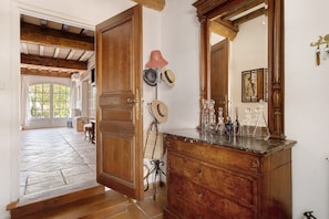 A hallway with a wooden door, a mirror, and a collection of hats and bottles on a shelf. - Holiday home 'Gîte Palmier - Le Trabet' with pool in the heart of the vineyards (Moussoulens)