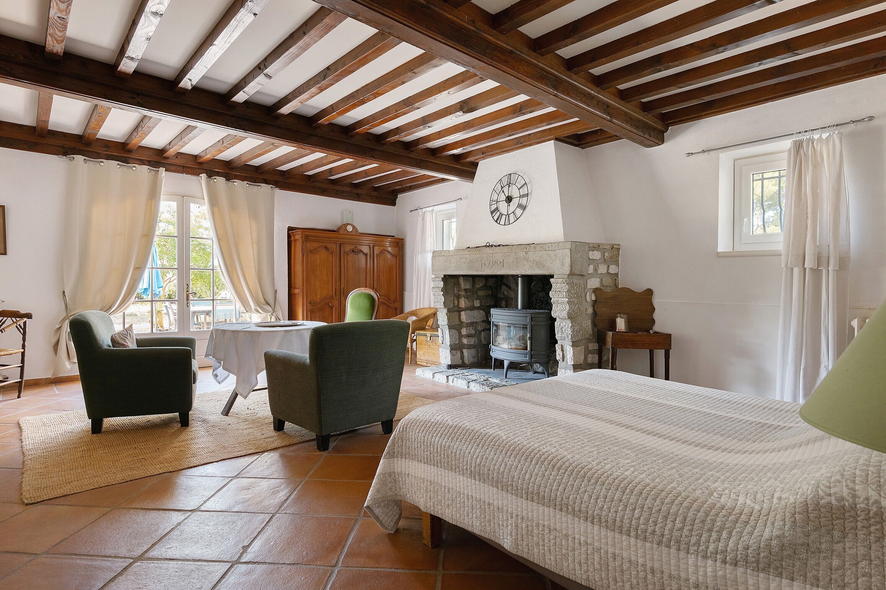 A room with a bed, a fireplace, a table, and a chair.