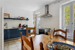 Eine moderne Küche mit weißen Ziegelwänden, einer blauen Arbeitsplatte und einem Essbereich mit Holztisch und -stühlen.