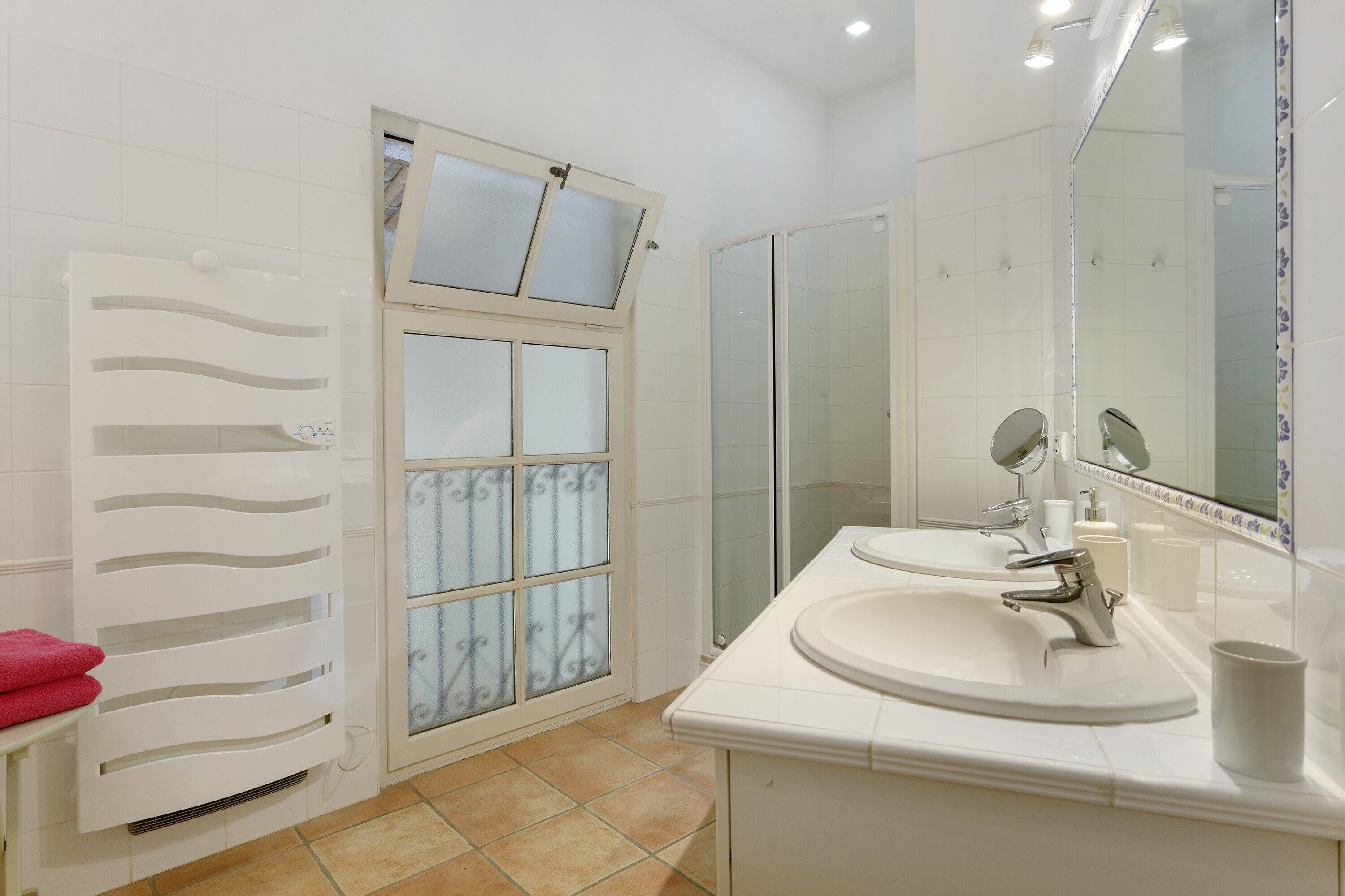 A bathroom with a shower, a sink, a mirror, and a towel rack.