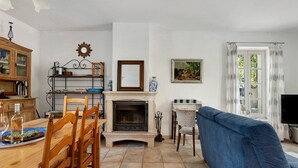 Ein Wohnzimmer mit Kamin, einem Essbereich mit Holztisch und -stühlen, einem blauen Sofa und einem Fernseher.
